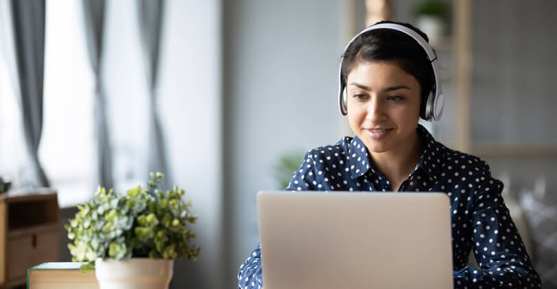 Young woman viewing a laptop with headphones on.