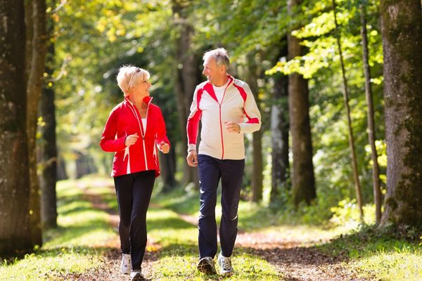 couple running on a paved trail among trees