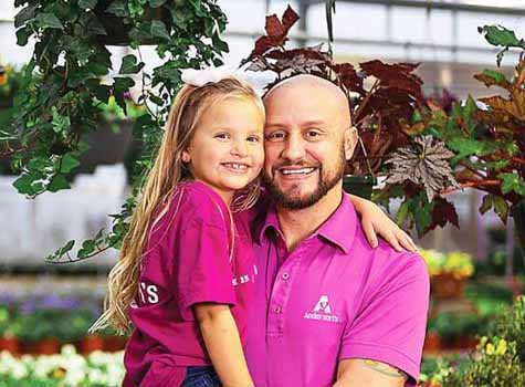 A business owner holding his daughter.