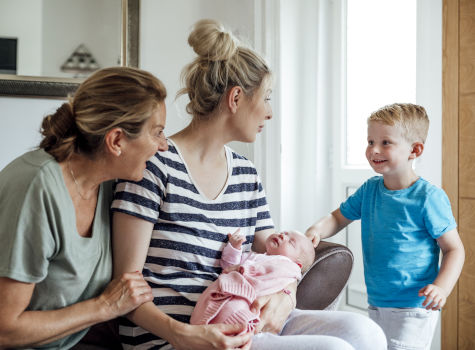 Two women talking to a boy while holding a swaddled baby.