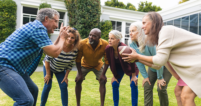 Senior man explaining rugby rules to senior friends in the backyard.