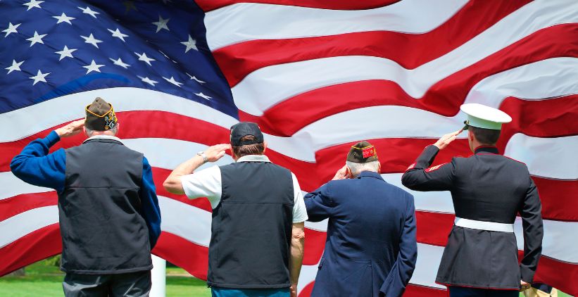 Soldier and veterans saluting American flag at Memorial Day Ceremony