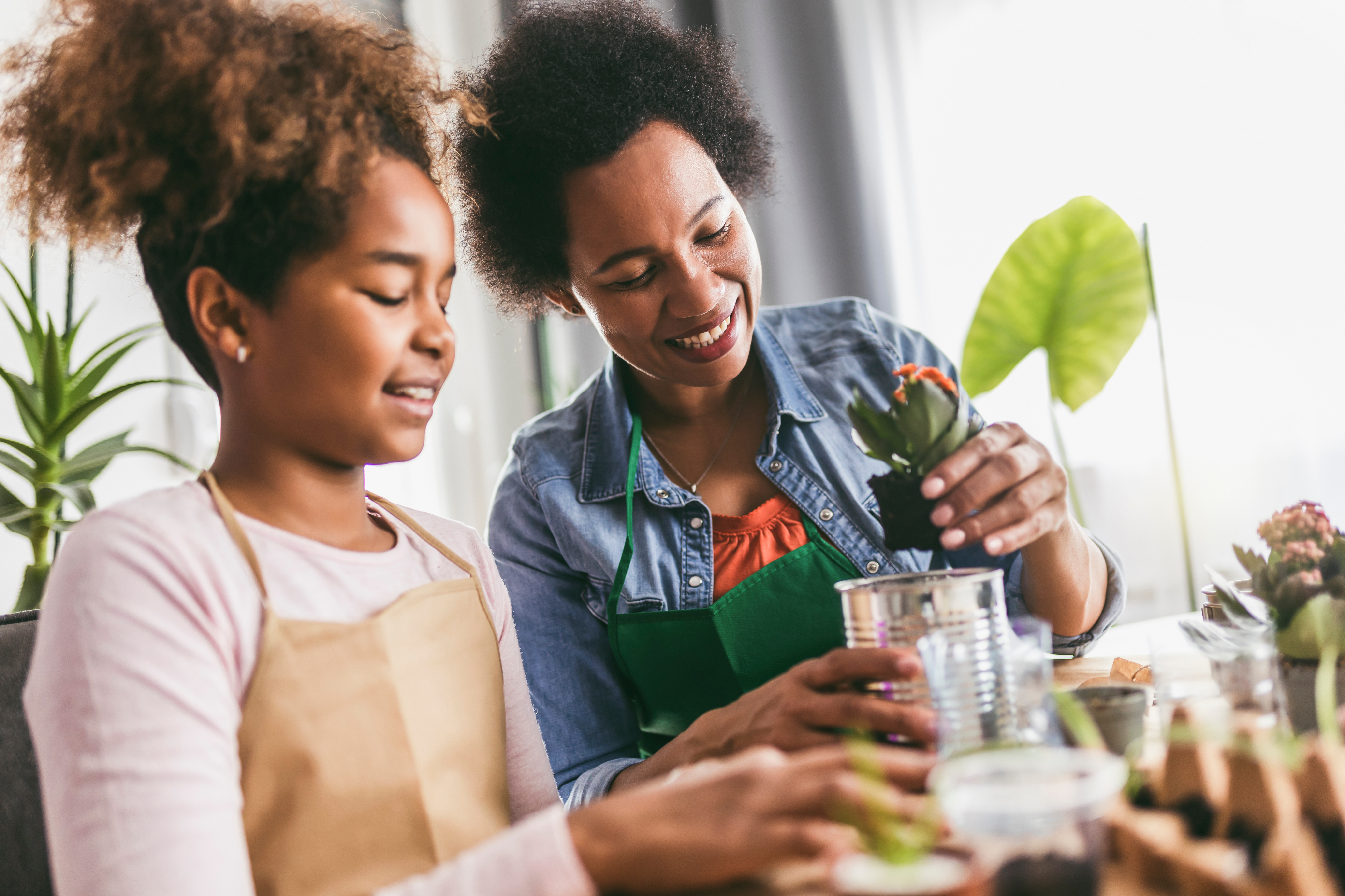 mother and daughter are planting seedlings in soil at their table