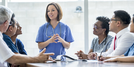 Female physician educating panel of medical professionals