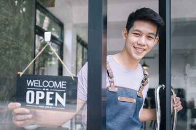 business owner standing in the doorway of his shop with a welcome