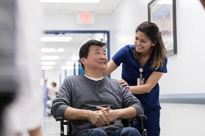 Man being pushed in wheelchair by nurse to be discharged from hospital