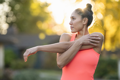 A happy, healthy woman stretching before exercising to meet her health goals.