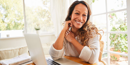 A happy woman getting cost estimates on her laptop computer.